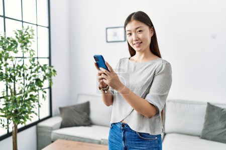 Photo for Young asian woman using smartphone at the living room - Royalty Free Image