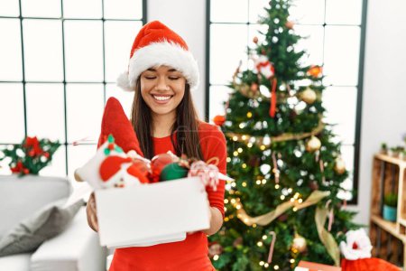 Photo for Young latin woman holding christmas tree decoration box at home - Royalty Free Image
