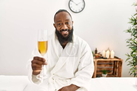 Photo for Young african american man smiling confident drinking champagne at beauty center - Royalty Free Image