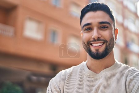 Foto de Hombre árabe joven sonriendo confiado de pie en la calle - Imagen libre de derechos