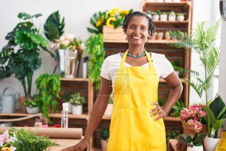 Téléchargez les photos : Moyen Age afro-américaine fleuriste souriant confiance debout à la boutique de fleurs - en image libre de droit