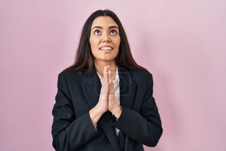 Photo for Young brunette woman wearing business style over pink background begging and praying with hands together with hope expression on face very emotional and worried. begging. - Royalty Free Image