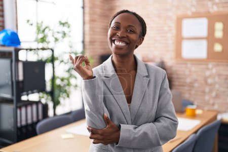 Photo for African american woman at the office smiling happy pointing with hand and finger to the side - Royalty Free Image