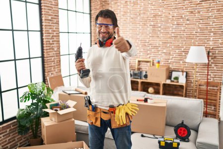 Photo for Handsome middle age man holding screwdriver at new home approving doing positive gesture with hand, thumbs up smiling and happy for success. winner gesture. - Royalty Free Image