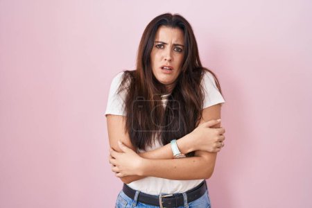 Photo for Young brunette woman standing over pink background shaking and freezing for winter cold with sad and shock expression on face - Royalty Free Image