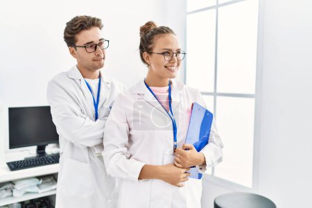 Foto de Hombre y mujer vistiendo uniforme científico sujetando portapapeles trabajando en laboratorio - Imagen libre de derechos