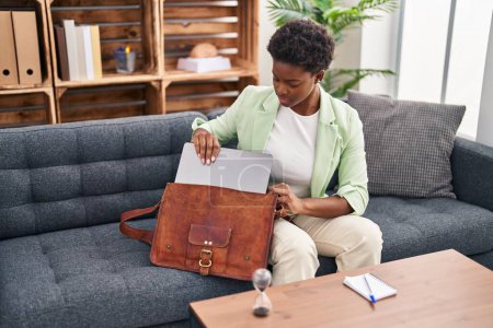 Photo for African american woman psychologist holding laptop of briefcase at psychology center - Royalty Free Image
