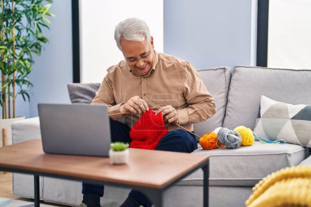 Photo for Senior man having online sew lesson sitting on sofa at home - Royalty Free Image