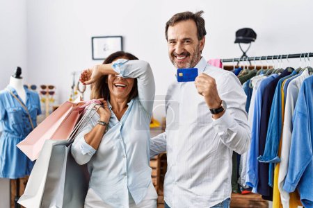 Photo for Hispanic middle age couple holding shopping bags and credit card smiling cheerful playing peek a boo with hands showing face. surprised and exited - Royalty Free Image
