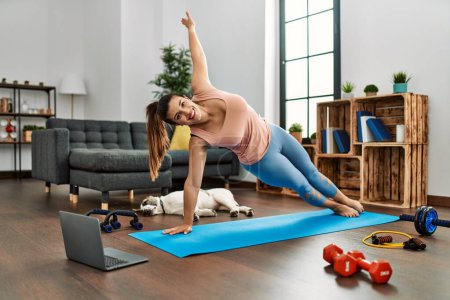 Téléchargez les photos : Jeune femme souriante confiante ayant cours de yoga en ligne à la maison - en image libre de droit