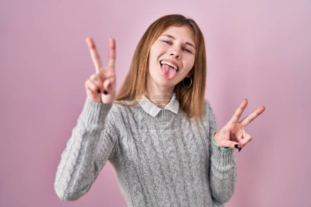 Photo for Beautiful woman standing over pink background smiling with tongue out showing fingers of both hands doing victory sign. number two. - Royalty Free Image