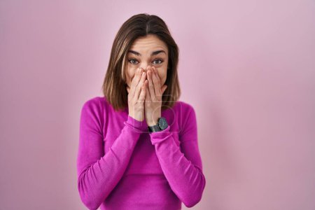Téléchargez les photos : Hispanic woman standing over pink background laughing and embarrassed giggle covering mouth with hands, gossip and scandal concept - en image libre de droit