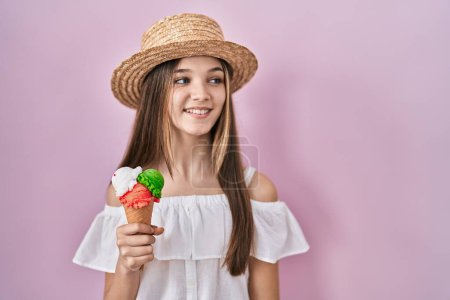 Téléchargez les photos : Adolescente tenant de la crème glacée regardant de côté avec le sourire sur le visage, expression naturelle. riant confiant. - en image libre de droit