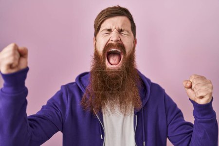 Téléchargez les photos : Homme caucasien avec une longue barbe debout sur fond rose célébrant fou et fou de succès avec les bras levés et les yeux fermés hurlant excité. concept gagnant - en image libre de droit