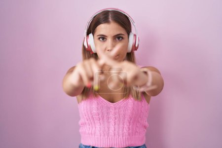 Téléchargez les photos : Young blonde woman listening to music using headphones rejection expression crossing fingers doing negative sign - en image libre de droit