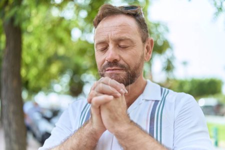 Photo for Middle age man praying with closed eyes at park - Royalty Free Image