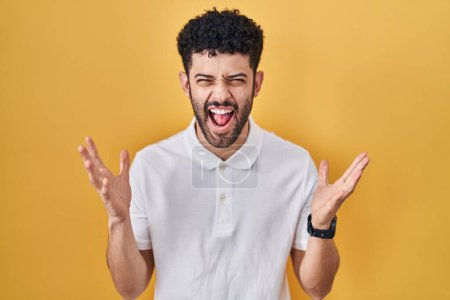 Téléchargez les photos : Homme arabe debout sur fond jaune célébrant fou et fou de succès avec les bras levés et les yeux fermés hurlant excité. concept gagnant - en image libre de droit