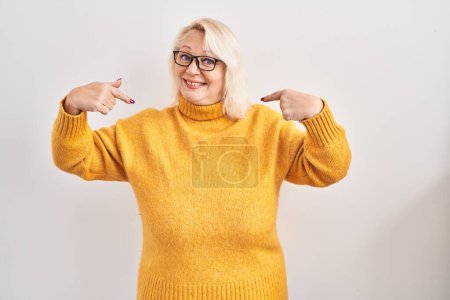 Téléchargez les photos : Moyen Age femme caucasienne portant des lunettes debout sur le fond regardant confiant avec le sourire sur le visage, se montrant du doigt fier et heureux. - en image libre de droit