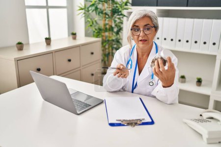 Téléchargez les photos : Femme d'âge moyen portant un uniforme de médecin prescrivent de la marihuana à la clinique - en image libre de droit