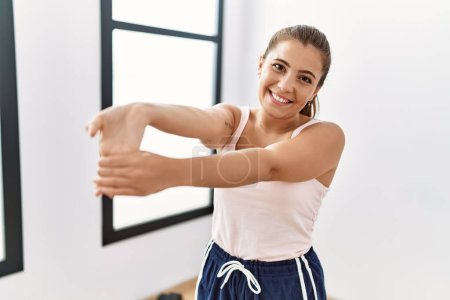 Photo for Young hispanic woman smiling confident stretching at sport center - Royalty Free Image