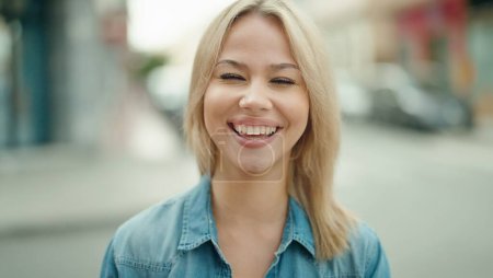 Téléchargez les photos : Jeune femme blonde souriante confiante debout dans la rue - en image libre de droit