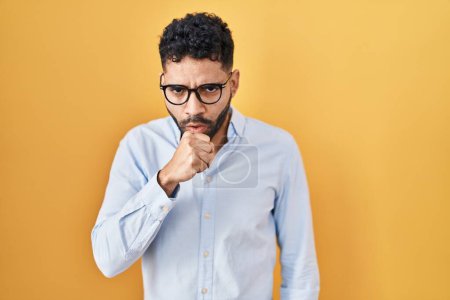 Photo for Hispanic man with beard standing over yellow background feeling unwell and coughing as symptom for cold or bronchitis. health care concept. - Royalty Free Image