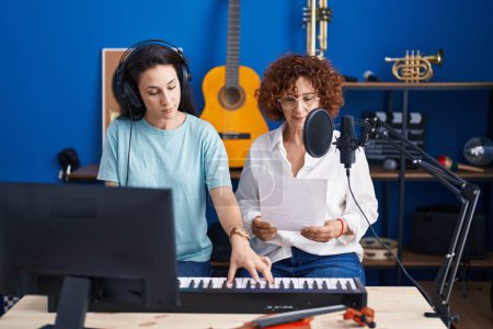 Foto de Dos mujeres músicos cantando canciones tocando el teclado de piano en el estudio de música - Imagen libre de derechos