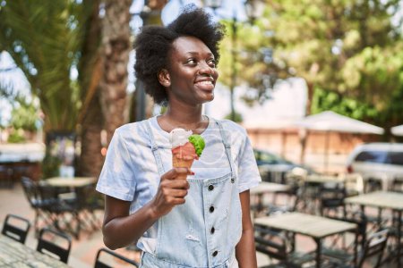 Foto de Young african woman smiling eating ice cream at street - Imagen libre de derechos