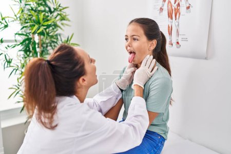 Foto de Mujer y niña médico y paciente examinando garganta en la clínica - Imagen libre de derechos