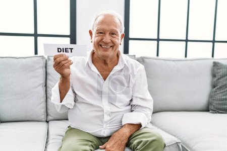Foto de Hombre mayor sosteniendo banner de dieta con aspecto positivo y feliz de pie y sonriendo con una sonrisa confiada mostrando los dientes - Imagen libre de derechos
