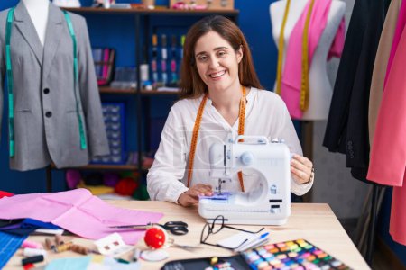 Téléchargez les photos : Young woman tailor smiling confident using sewing machine at sewing studio - en image libre de droit