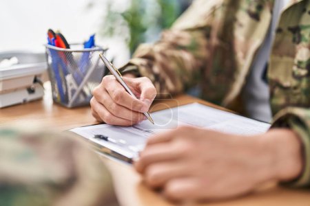 Téléchargez les photos : Jeune homme hispanique soldat de l'armée signant un contrat au bureau - en image libre de droit