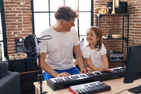 Foto de Father and daughter playing piano keyboard at music studio - Imagen libre de derechos