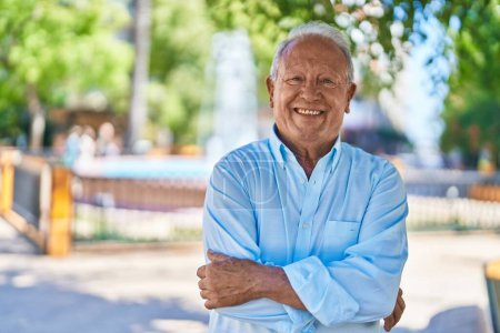 Photo for Senior grey-haired man smiling confident standing with arms crossed gesture at park - Royalty Free Image