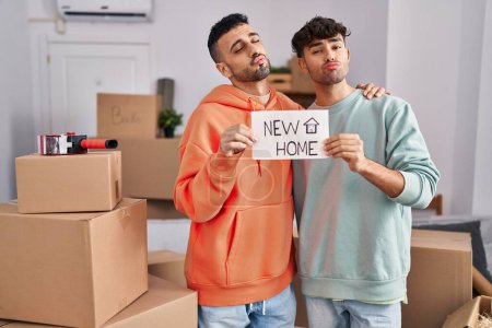 Photo for Young hispanic gay couple moving to a new home looking at the camera blowing a kiss being lovely and sexy. love expression. - Royalty Free Image