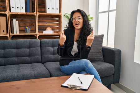 Photo for Young asian woman at consultation office showing middle finger doing fuck you bad expression, provocation and rude attitude. screaming excited - Royalty Free Image