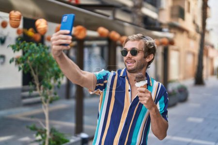 Photo for Young man tourist holdng ice cream make selfie by smartphone at street - Royalty Free Image