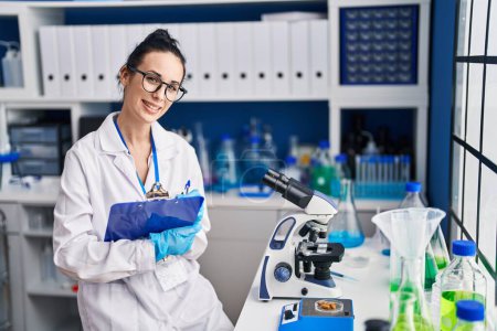 Photo for Young caucasian woman scientist weighing pills writing on document at laboratory - Royalty Free Image