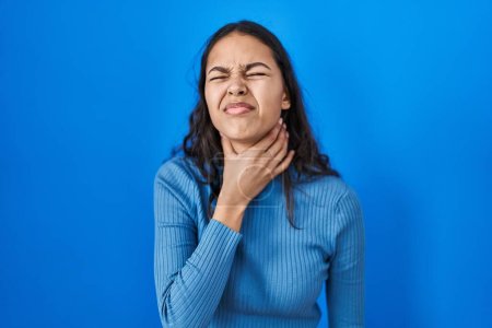 Photo for Young brazilian woman standing over blue isolated background touching painful neck, sore throat for flu, clod and infection - Royalty Free Image