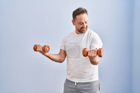 Photo for Young caucasian man smiling confident using dumbbells training at sport center - Royalty Free Image
