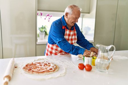 Photo for Senior man smiling confident cooking pizza at kitchen - Royalty Free Image