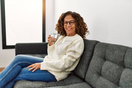 Photo for Middle age hispanic woman smiling confident drinking water at home - Royalty Free Image