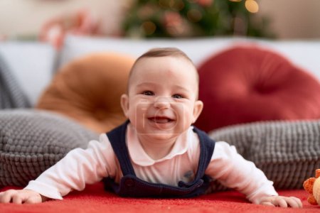 Photo for Adorable toddler smiling confident lying on sofa by christmas tree at home - Royalty Free Image