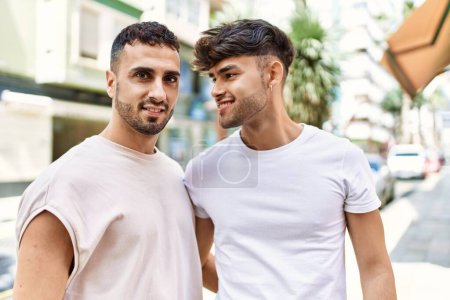 Téléchargez les photos : Deux hommes hispaniques couple souriant confiant étreinte l'un l'autre debout à la rue - en image libre de droit