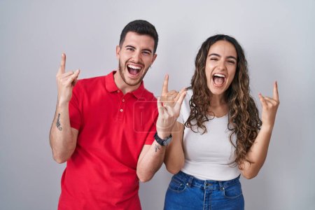 Photo for Young hispanic couple standing over isolated background shouting with crazy expression doing rock symbol with hands up. music star. heavy music concept. - Royalty Free Image