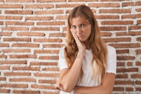 Téléchargez les photos : Young caucasian woman standing over bricks wall thinking looking tired and bored with depression problems with crossed arms. - en image libre de droit