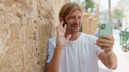 Photo for Young blond man smiling confident having video call at street - Royalty Free Image
