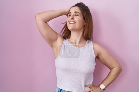 Photo for Brunette woman standing over pink background smiling confident touching hair with hand up gesture, posing attractive and fashionable - Royalty Free Image