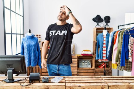 Téléchargez les photos : Jeune homme hispanique travaillant à la boutique de détail très heureux et souriant regardant loin avec la main sur la tête. concept de recherche. - en image libre de droit
