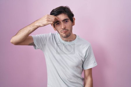 Photo for Young hispanic man standing over pink background pointing unhappy to pimple on forehead, ugly infection of blackhead. acne and skin problem - Royalty Free Image